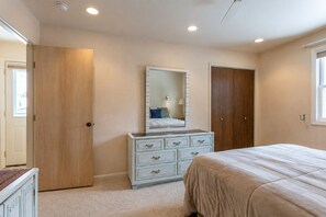 Une chambre à coucher comprenant un lit, une commode, un miroir et deux portes.