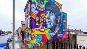 A colorful mural on a building with a large portrait and various abstract designs. - Beatles Themed Hotel (Liverpool)