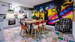 A modern kitchen with a dining area, featuring a colorful abstract mural on the wall and a patterned tile floor. - Beatles Themed Hotel (Liverpool)