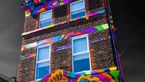 A multi-story building with vibrant, colorful graffiti art on its facade. - Beatles Themed Hotel (Liverpool)