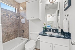 Ein modernes Badezimmer mit Badewanne, Toilette und Waschtisch mit Waschbecken und Spiegel.