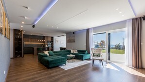 Amplia sala de estar con sofá modular, una mesa de centro redonda y un comedor.
