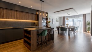 Una cocina moderna con una isla central, taburetes de bar y una zona de comedor con mesa y sillas.