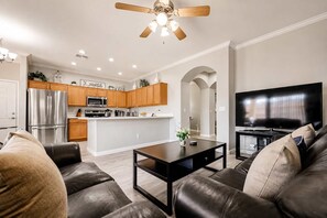 A modern living room with a black leather sofa, a coffee table, and a flat-screen TV.