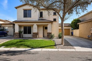 A two-story residential building with a front lawn, a driveway, and a garage. - Pet-Friendly 3BR | Fenced Yard | King Bed (Chandler)