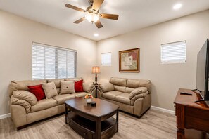 A living room with two sofas, a coffee table, a ceiling fan, and a television. - Pet-Friendly 3BR | Fenced Yard | King Bed (Chandler)