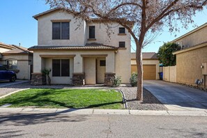 A two-story house with a tiled roof, a front porch, and a small front yard.