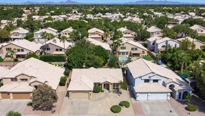 A residential area with houses featuring pitched roofs, surrounded by greenery and a clear sky.