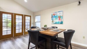 A dining area with a wooden table, black chairs, and a colorful abstract painting on the wall. - Immaculate!  Single-Story 3bdr | Chandler (Chandler)