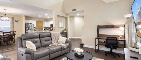 A modern living room with a gray sofa, a round coffee table, and a desk with a chair.