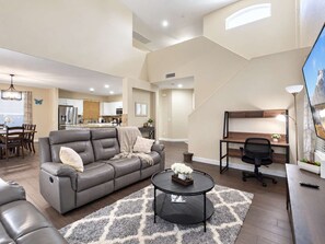 Un salon moderne avec un canapé gris, une table basse ronde et un bureau avec une chaise.