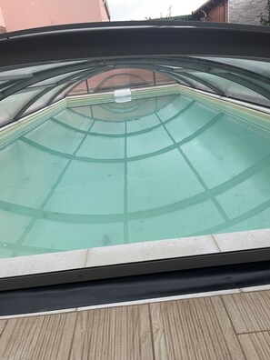 A view of a swimming pool with a glass bottom and a wooden deck surrounding it.
