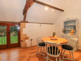 Un comedor acogedor con una mesa y sillas de madera, un cuenco de fruta y una pared de piedra.