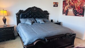 Ein Schlafzimmer mit einem dunklen, hölzernen Himmelbett, einem Nachttisch mit Lampe und einem gerahmten Foto an der Wand.