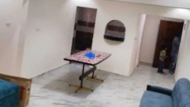 A room with a small table, a sofa, and a door leading to another room.