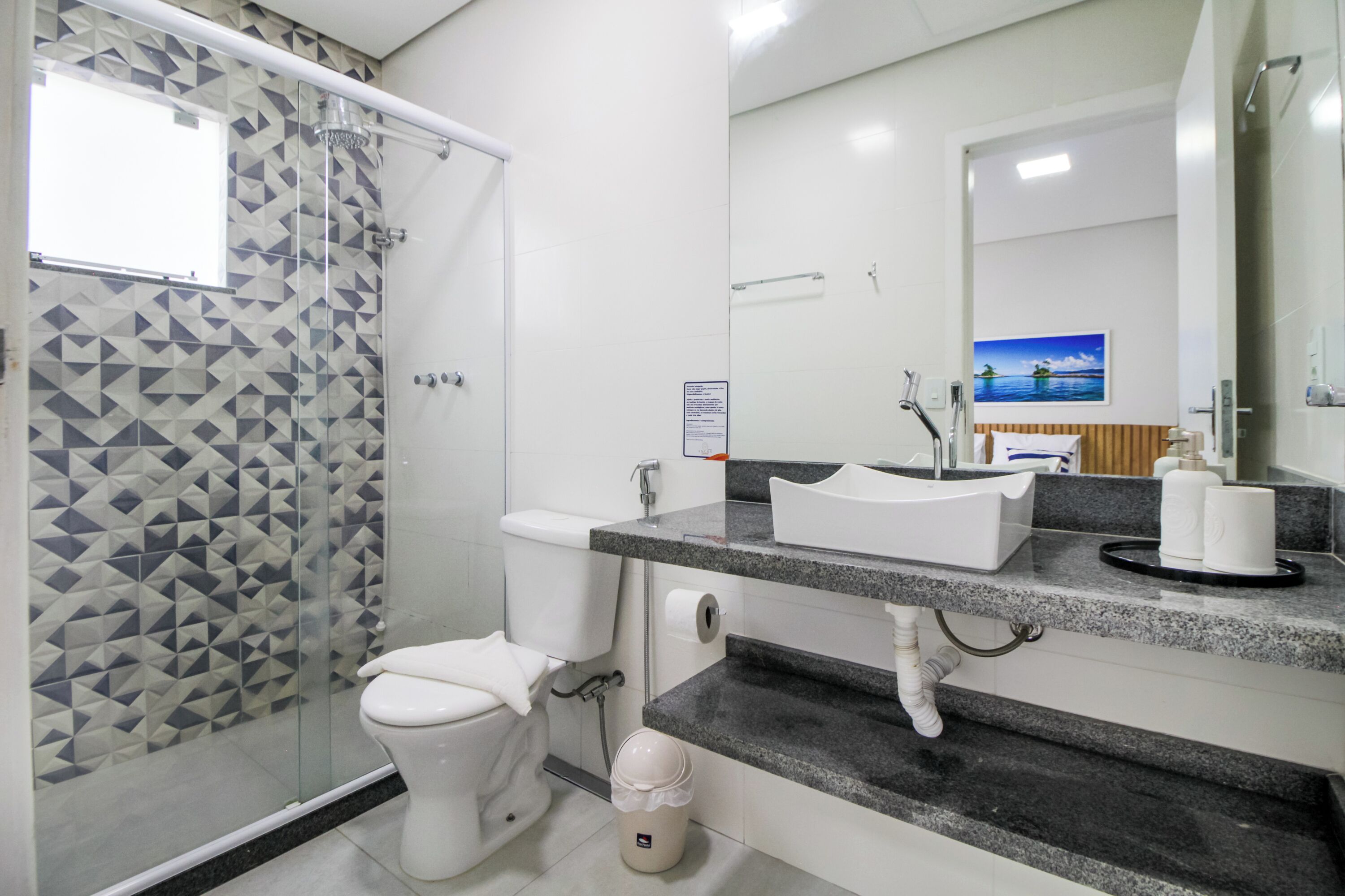 A modern bathroom with a shower, toilet, sink, and a large mirror.