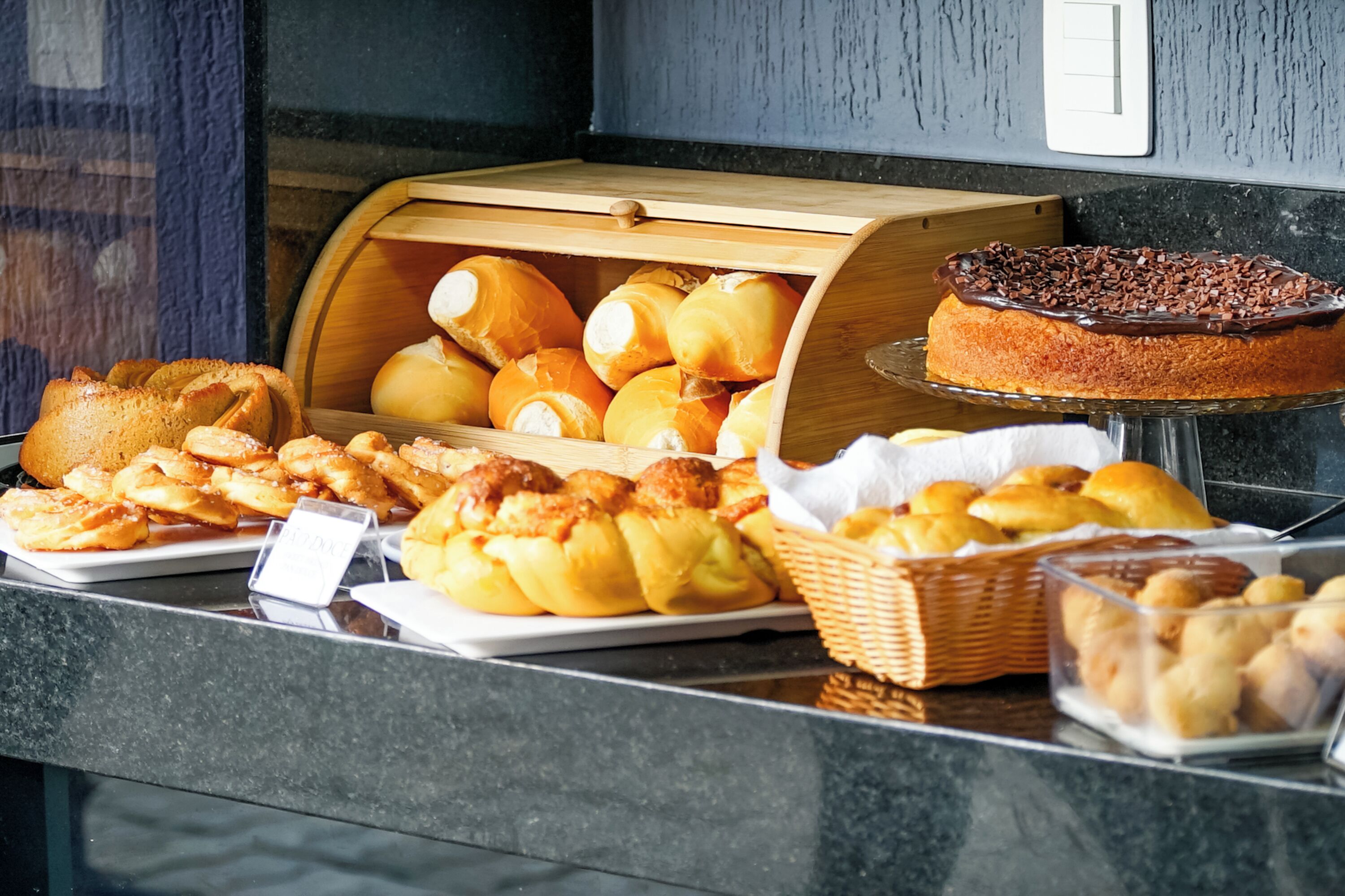 A buffet with various baked goods including bread, rolls, and pastries.