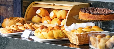 Un bufé con diversas opciones de panadería, incluyendo pan, bollos y pasteles.
