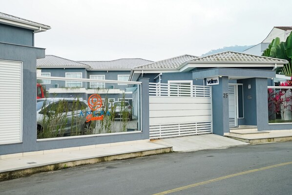 A modern building with a gated entrance, a visible sign for 'velrn', and a clear view of parked cars through the window.