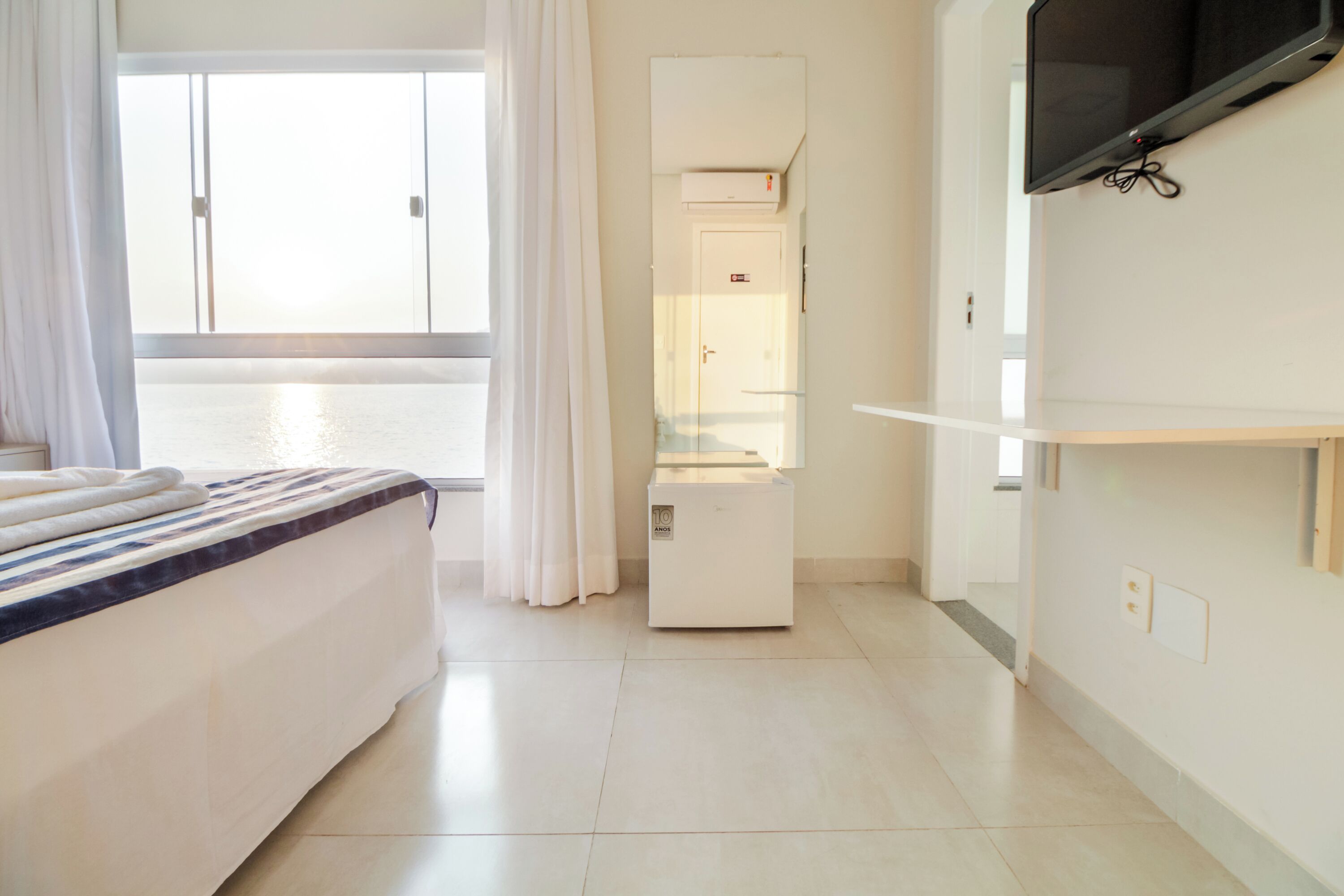 A hotel room with a bed, a television mounted on the wall, and a door leading to a bathroom.