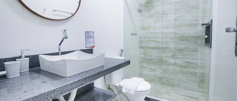 A modern bathroom with a granite countertop, a white sink, and a glass shower enclosure.