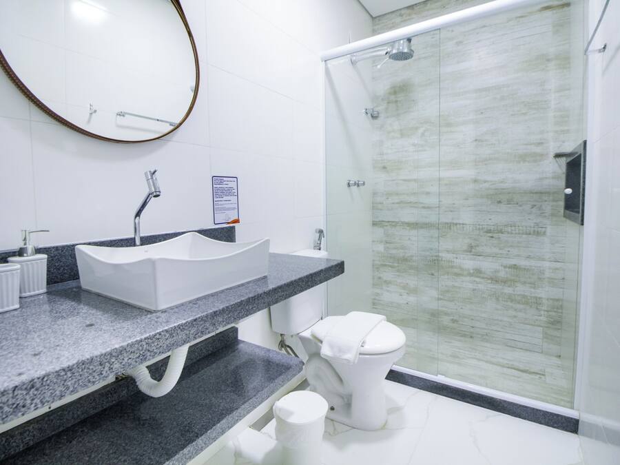 A modern bathroom with a granite countertop, a white sink, and a glass shower enclosure.