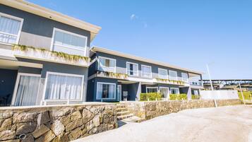 A modern multi-story residential building with a stone retaining wall and a clear sky.