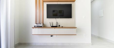 A modern living room with a flat-screen TV mounted on a wooden shelf above a white console table.
