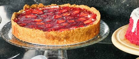 A dessert display with a strawberry tart on a glass stand.