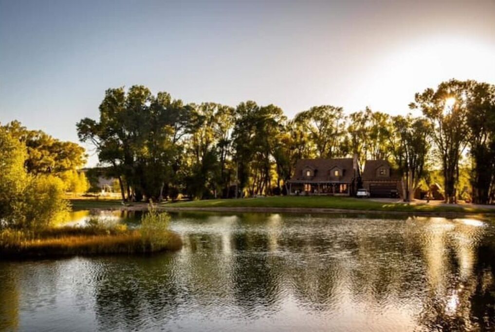 Una casa a la vora d'un llac, amb el seu reflex a l'aigua.