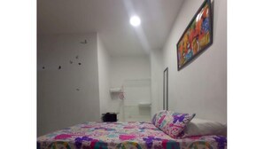 Un dormitorio con una cama, aire acondicionado de pared y un cuadro colorido.