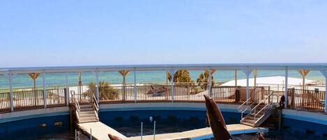 A pool area with dolphins performing tricks, a clear view of the ocean, and a covered deck with seating.