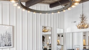 Ein modernes Wohnzimmer mit einem Ecksofa, einem Marmortisch und einer außergewöhnlichen, runden Leuchte.