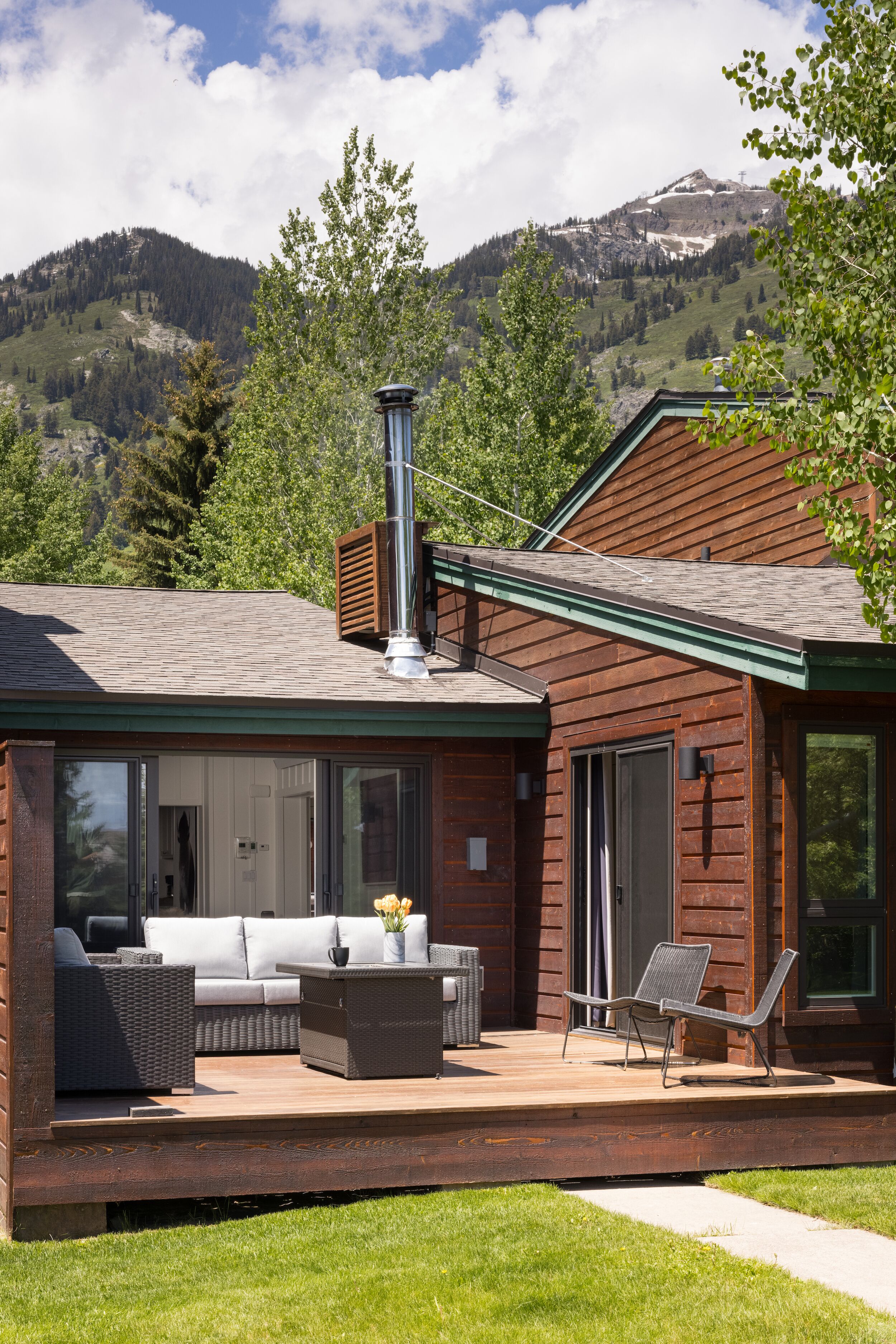 Ein modernes Haus mit Terrasse, Sitzgelegenheit im Freien und Blick auf Berge.