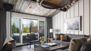 Ein modernes Wohnzimmer mit Kamin, einer Couch, einem Couchtisch und Blick ins Freie.