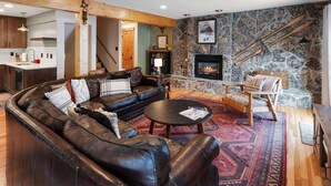 A cozy living room with a stone fireplace, leather sofa, and a wooden coffee table.