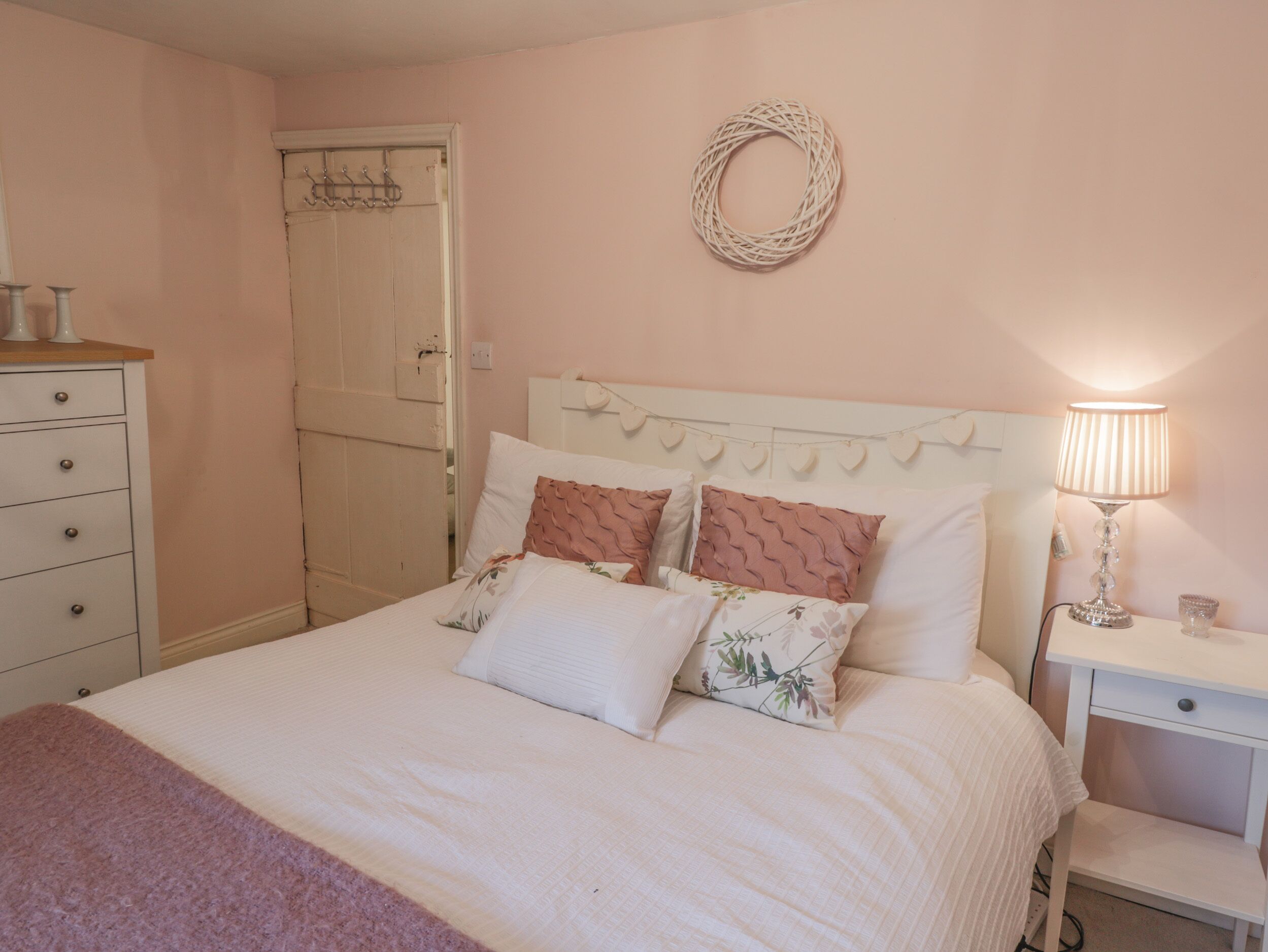 Un dormitorio con cama, mesita de noche, lámpara y cómoda.