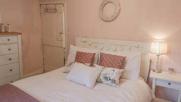 Un dormitorio con cama, mesita de noche, lámpara y cómoda.