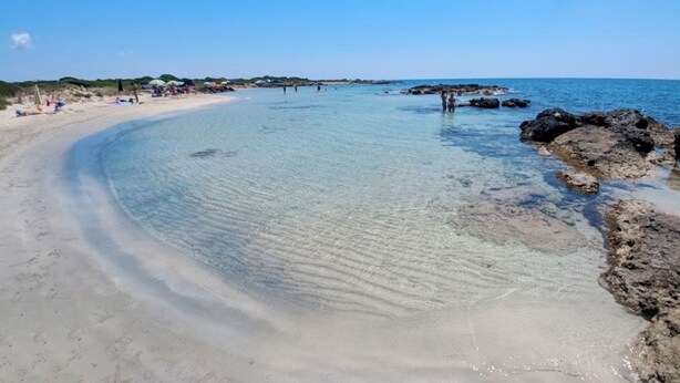 A beach with clear shallow waters, sandy shore, and rocky outcrops. - Pugliacasealmare Rif. 1317 (Torre Pali)