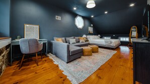 Un dormitorio moderno con un sofá gris, dos camas, un escritorio y una silla.
