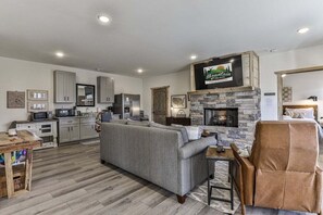 A modern living room with a stone fireplace, grey sofa, and a television mounted above it.