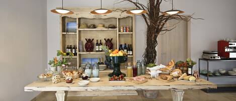 A dining table with food and drinks, surrounded by shelves with bottles and a large vase.