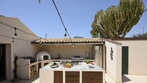 An outdoor kitchen area with a pizza oven, grill, and various food items.
