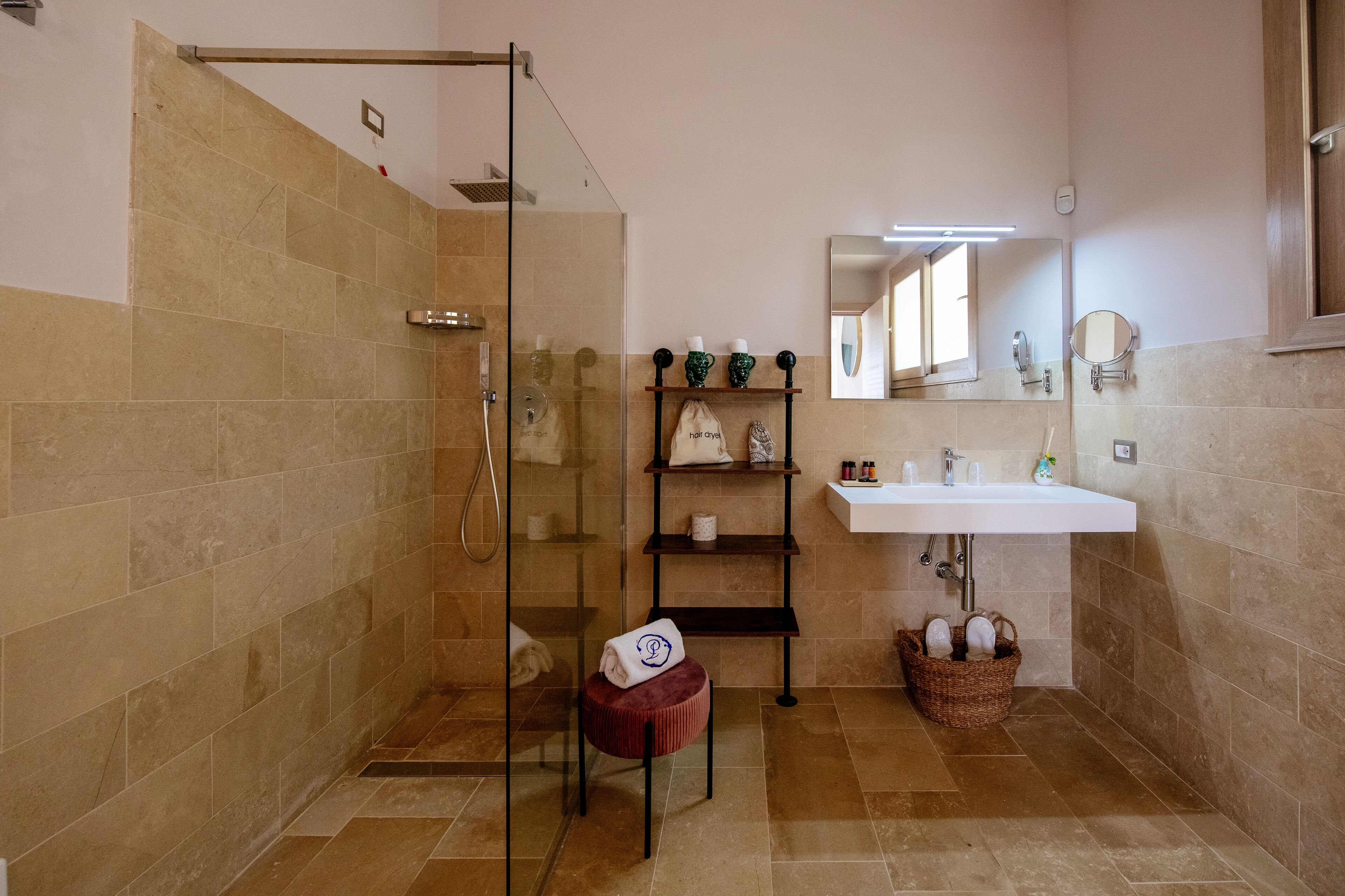 Ein Badezimmer mit einer Duschkabine, einem Waschbecken mit Spiegel und Ablagen für Toilettenartikel.