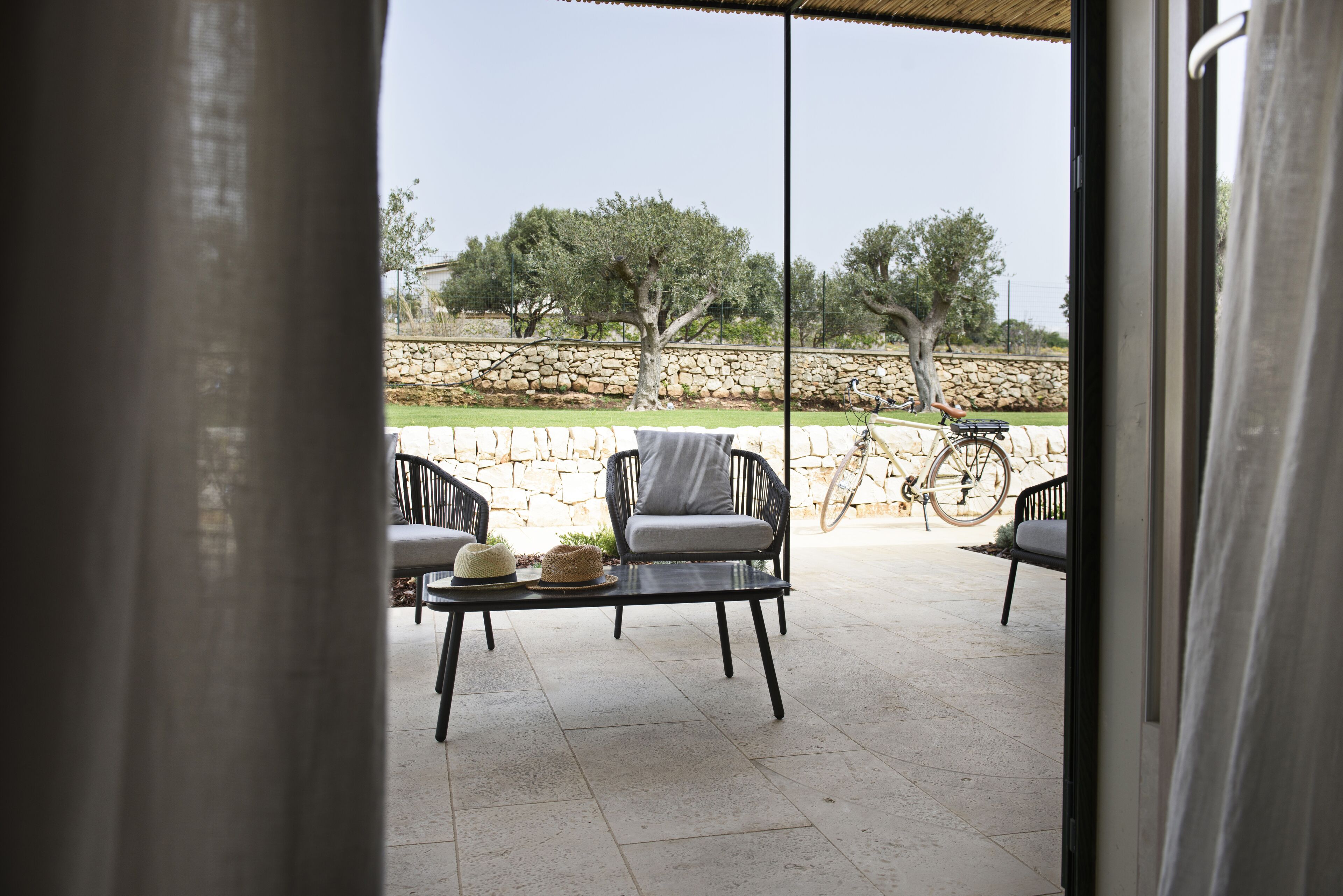 An outdoor patio with two black chairs, a small table, and a bicycle.