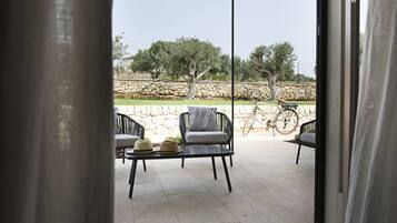 An outdoor patio with two black chairs, a small table, and a bicycle.