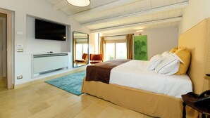 A modern bedroom with a large bed, a flat-screen TV, a mirror, and a window with curtains.