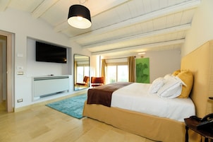 Un dormitorio moderno con una cama grande, un televisor de pantalla plana, un espejo y una ventana con cortinas.
