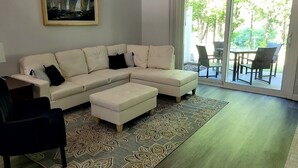 A living room with a beige sectional sofa, a patterned rug, and a painting on the wall. - Natures Get-A-Way in Historical Excelsior (Excelsior)