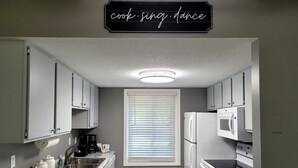 A compact kitchen with white cabinets, a marble countertop, a built-in oven, and a microwave. - Natures Get-A-Way in Historical Excelsior (Excelsior)